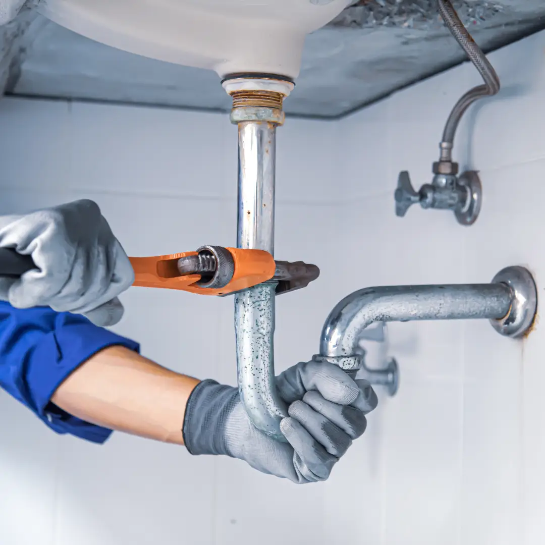 Plumber fixing pipes under sink